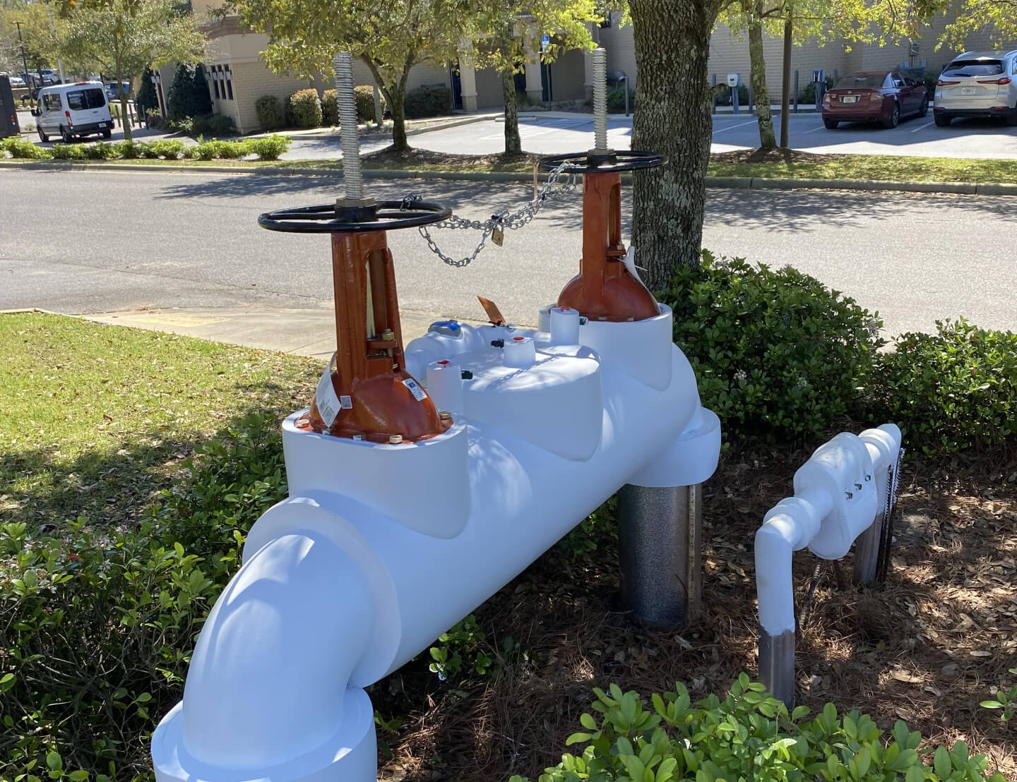 A large white backflow preventer installed near a tree trunk.